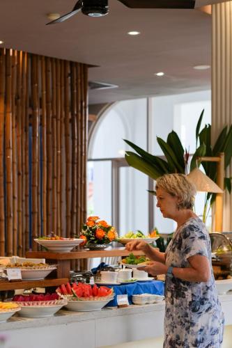 a woman is standing in front of a buffet at Alba Spa Hotel in Hue
