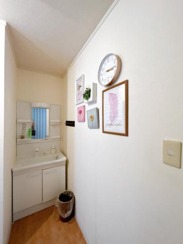 a bathroom with a sink and a clock on a wall at Condominium Palace Resort Chatan III in Chatan