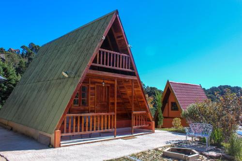 a log cabin with a green roof at Recanto do Bosque in Campos do Jordão