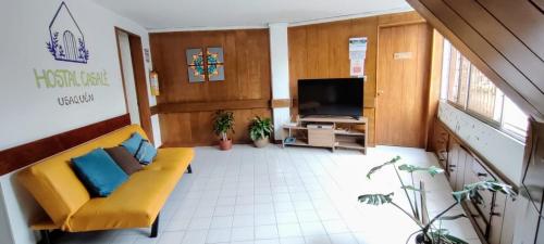 a living room with a yellow couch and a tv at Hostal CasAlé Usaquén in Bogotá