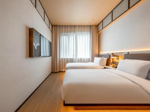 a hotel room with two beds and a window at Beijing Renjoy Hotel in Beijing