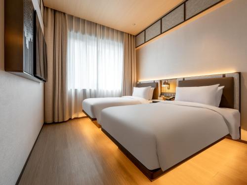 two beds in a hotel room with a window at Beijing Renjoy Hotel in Beijing