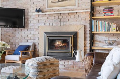 a living room with a brick wall with a fireplace at Bluewave Beach Getaway in Wamberal North