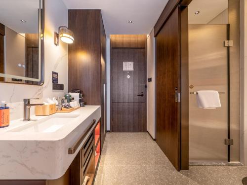a bathroom with a sink and a mirror and a door at Beijing Renjoy Hotel in Beijing