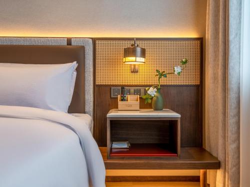 a bedroom with a bed and a side table with a lamp at Beijing Renjoy Hotel in Beijing