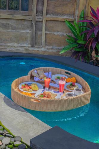 a table with food and drinks in a swimming pool at Abian Ubud View in Ubud