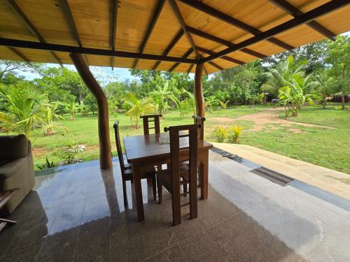 a wooden table and chairs under a pavilion at Ceylon Resort Wilpattu in Wilpattu
