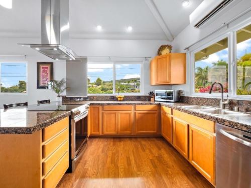 a kitchen with wooden cabinets and counters and windows at Central Oceanview Modern Cozy 3 Bed House in Kailua-Kona