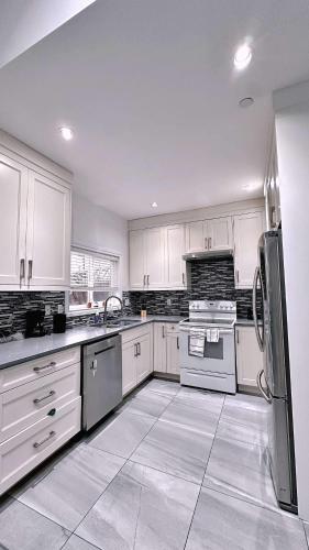 a large kitchen with white cabinets and appliances at The warm and lovely coach home in Vancouver