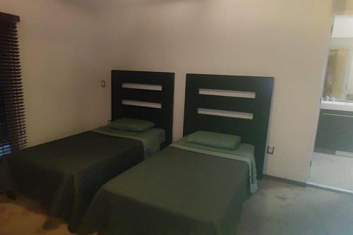 two twin beds in a room with green covers at Comodidad y Confort en Morelia in Morelia