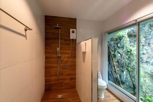 a bathroom with a shower and a toilet and a window at Rock and Tree House Resort in Khao Sok