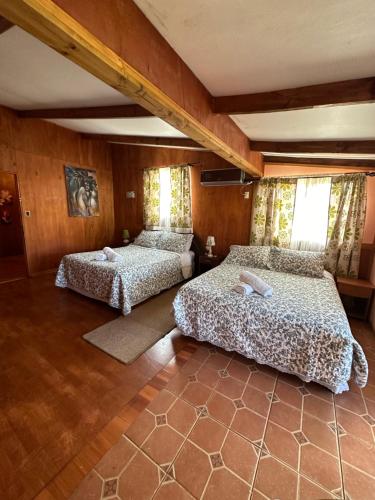 two beds in a room with wooden walls at Hare Henua Boutique in Hanga Roa