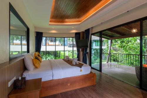 a bedroom with a large bed and a balcony at Rock and Tree House Resort in Khao Sok