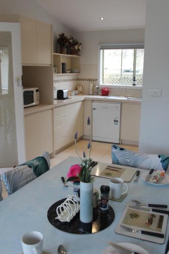 una cucina con tavolo e fiore di Courtsidecottage Bed and Breakfast a Euroa