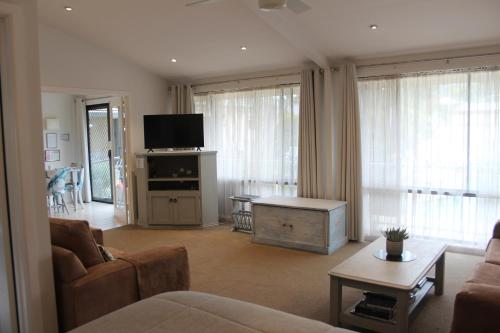 a living room with a couch and a tv at Courtsidecottage Bed and Breakfast in Euroa