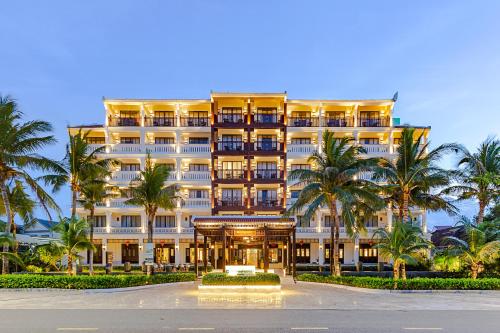 a large building with palm trees in front of it at Wyndham Garden Hoi An Cua Dai Beach in Hoi An