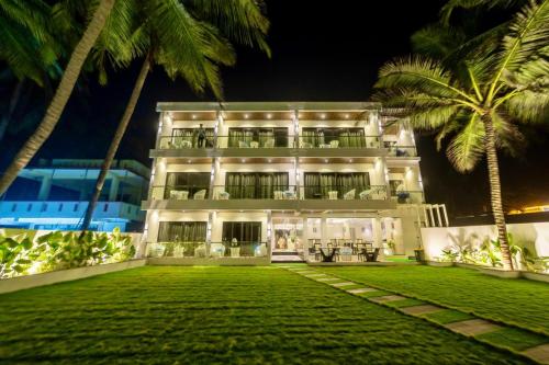 a building with palm trees in front of it at The Atlantis Devbag in Malvan