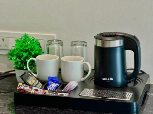 a coffee maker and two cups on a table at The Atlantis Devbag in Malvan