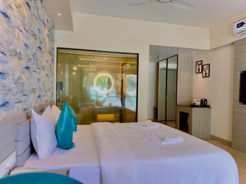 a bedroom with a large white bed with blue pillows at The Atlantis Devbag in Malvan