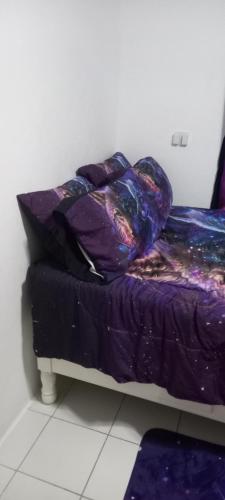 a bed with a purple comforter and pillows at Holiday rooms in St Thomas Jamaica in Clifton