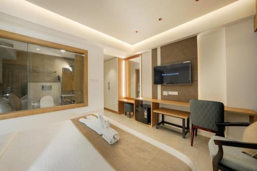 a room with a bathroom with a television and a chair at Aurora Hotels and Resorts in Pulickamaly