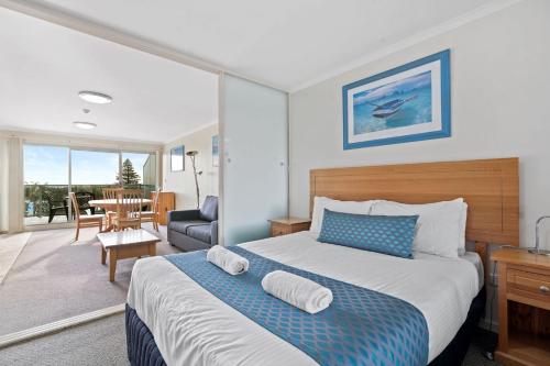 a bedroom with a bed and a living room at Nesuto Apartments - Unit 631 in The Entrance