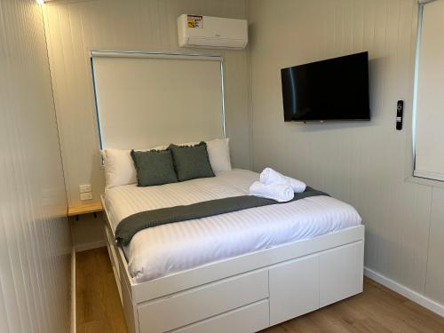 a small bedroom with a bed with a tv on the wall at Bellinger River Tourist Park in Repton