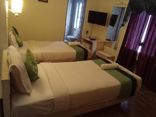 a hotel room with two beds and a television at Hotel Crown in Ahmedabad