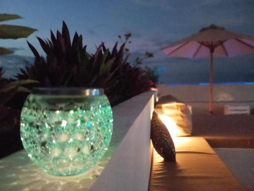 a green glass vase sitting on a wall with a plant at Aluna Beach Apartments in Nungwi