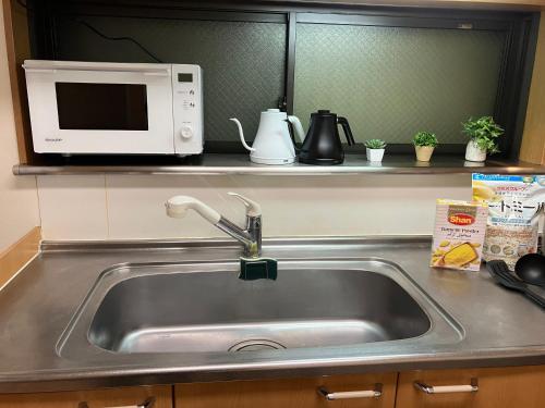 a sink in a kitchen with a microwave at Entire Hotel Beside Asakusa, Ueno, Akihabara and Tokyo Skytree tower between 3 Train Stations and Contains 3 Bedrooms, 2 Bathrooms and 2 toilets for 14 guests in Tokyo