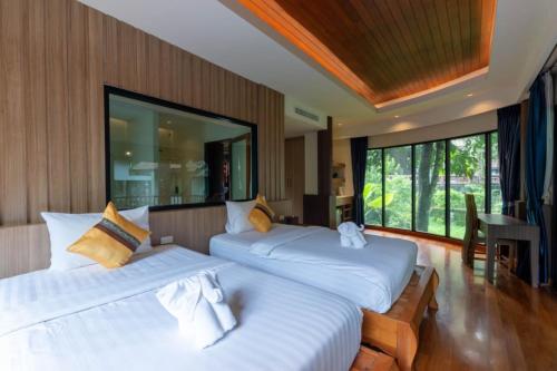 a bedroom with two beds and a large window at Rock and Tree House Resort in Khao Sok