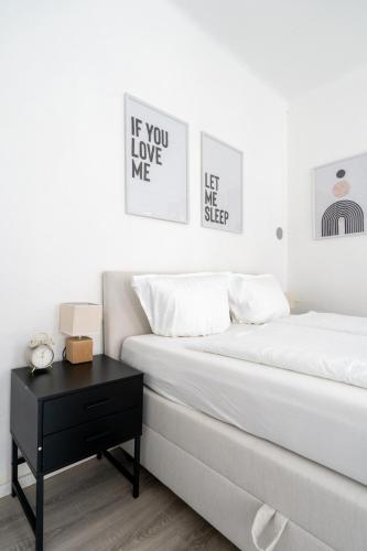 a white bedroom with a bed and a black table at COY Apartments Leoben - Stay Comfortable & Work Smart in Leoben