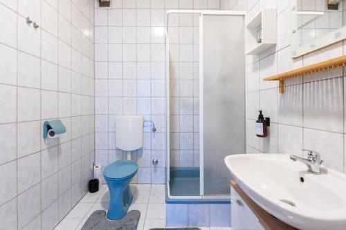 a bathroom with a blue toilet and a sink at COY Apartments Leoben - Stay Comfortable & Work Smart in Leoben