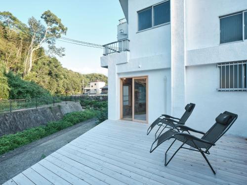 two chairs sitting on a deck in front of a building at 三笠館Mikasakan 別館 in Kinokawa
