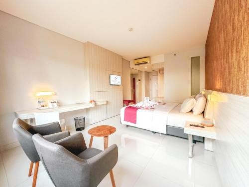 a bedroom with a bed and two chairs and a table at Sahid Bandara Soekarno Hatta in Tangerang