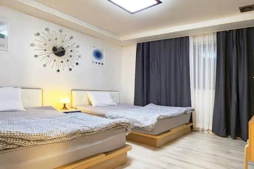 a bedroom with two beds and a clock on the wall at S1 Private Kintex Daehwadong in Goyang