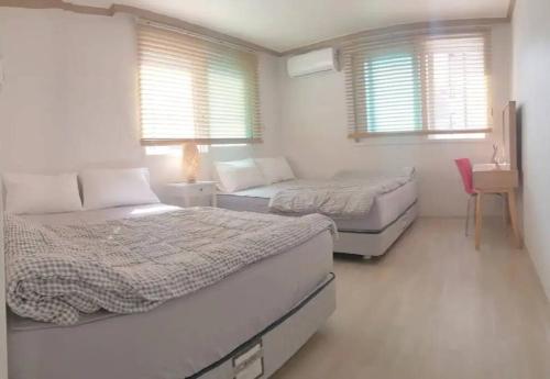 a bedroom with two beds and a table and two windows at S3 Private Kintex Daehwadong in Goyang