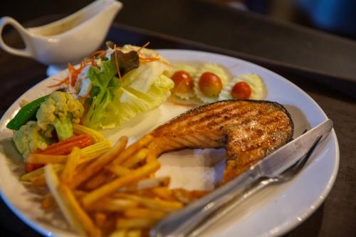 a plate of food with a piece of fish and french fries at Rock and Tree House Resort in Khao Sok