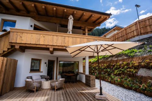 an umbrella on a wooden deck with a house at Premium-Twin-Lofts in Mieders