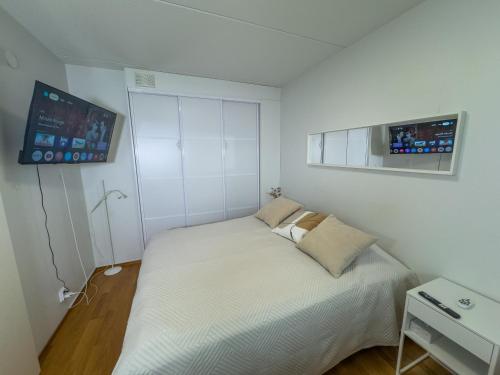 a small bedroom with a bed and a tv at Top floor flat with sauna, A/C & free parking in Vantaa