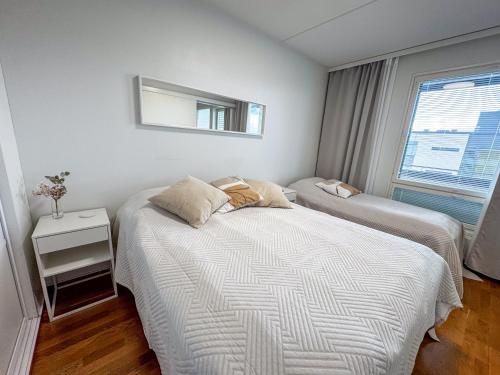a bedroom with two beds and a mirror on the wall at Top floor flat with sauna, A/C & free parking in Vantaa