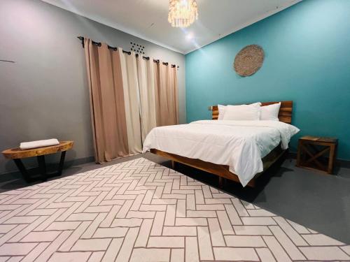 une chambre avec un lit et un mur bleu dans l'établissement City Retreat Arusha, à Arusha