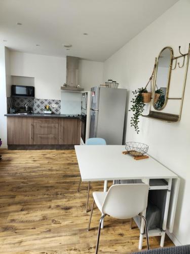 - une cuisine avec une table et des chaises blanches dans l'établissement Agréable appartement à CAMBO LES BAINS, à Cambo-les-Bains