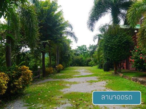 a path in a garden with palm trees at ศศิคันทรี รีสอร์ท in Suan Phung