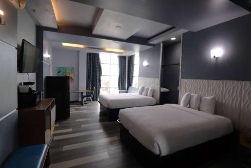 a hotel room with two beds and a television at Days Inn & Suites by Wyndham Milwaukee in Milwaukee