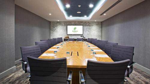 a large conference room with a long table and purple chairs at Holiday Inn Manchester - City Centre by IHG in Manchester