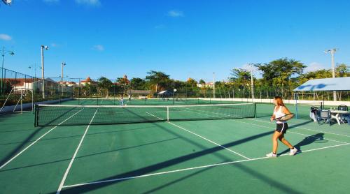 a woman is playing tennis on a tennis court at Occidental Caribe - All Inclusive in Punta Cana