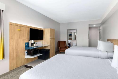 a hotel room with two beds and a television at Microtel Inn & Suites by Wyndham Lachute in Lachute
