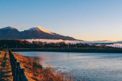 a view of a lake with a mountain in the background at 女性のための森サウナ 一棟貸し宿 SORA 宙 Forest sauna villa SORA in Komoro