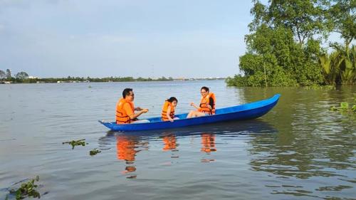 three people in a blue canoe on the water at Cồn Phụng Resort Mekong - Nature Escape with Free Boat Shuttle & Fishing in Ben Tre